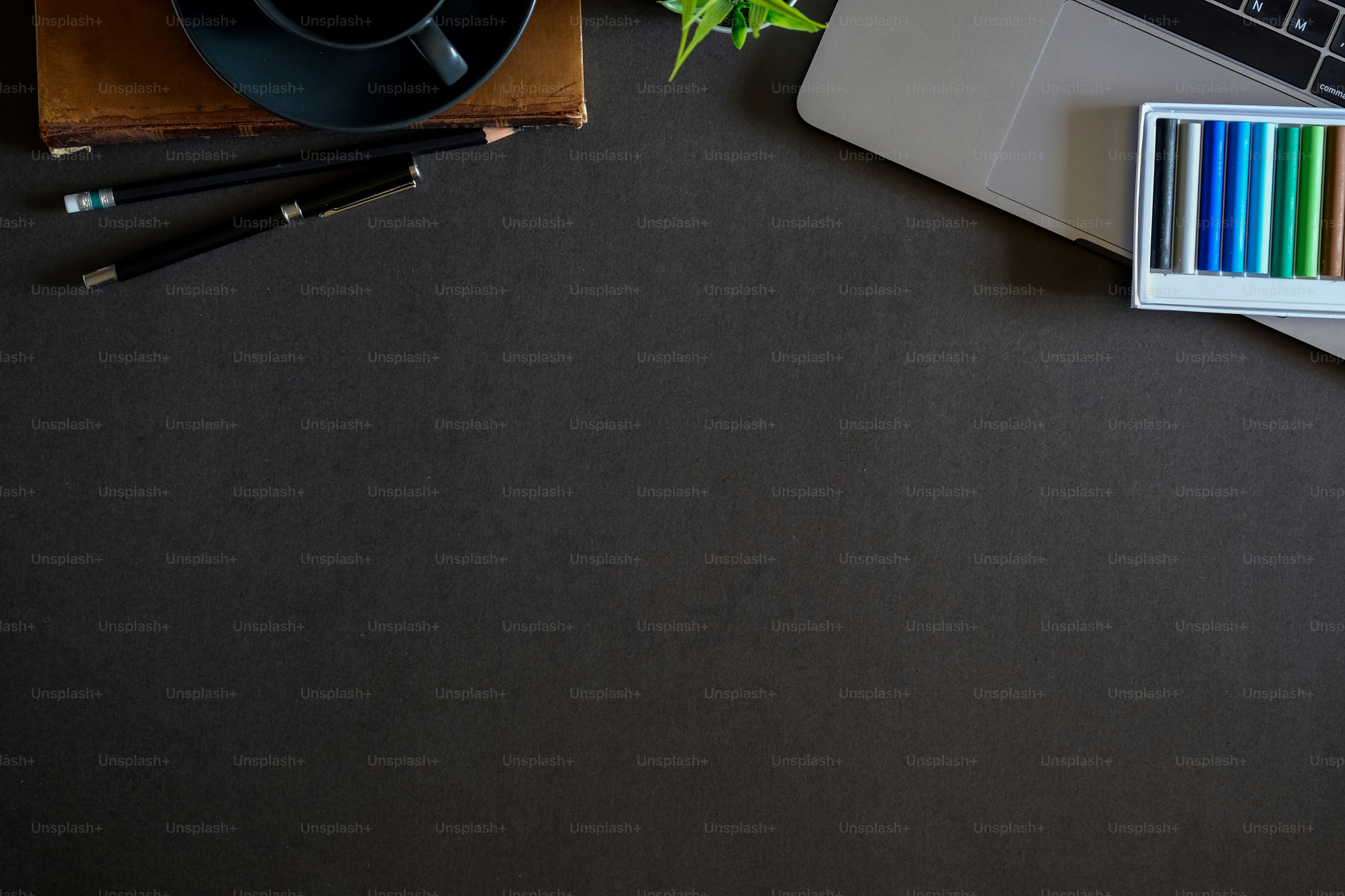 Designer workspace top view with essential elements on dark wooden board.